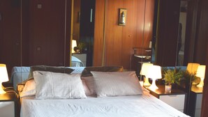 A neatly made bed with a checkered bedspread, a bedside lamp, and a small potted plant on the nightstand. - Duplex of 90m2, 6 persons with terrace of 30m2 (Barcelona)