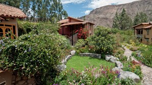 A courtyard with a stone pathway, surrounded by lush greenery and flowering plants. - Willka T'ika Essential Wellness (Urubamba)