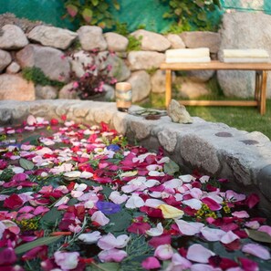 A garden with a stone pathway, a wooden table, and a stone wall with plants. - Willka T'ika Essential Wellness (Urubamba)