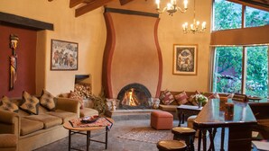 A cozy living room with a fireplace, a sofa, a coffee table, and a dining area with a table and chairs. - Willka T'ika Essential Wellness (Urubamba)