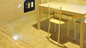 A kitchen with wooden cabinets, a stove, and a dining table with chairs.