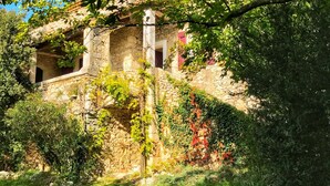 Un edificio de piedra con encanto rústico, rodeado de exuberante vegetación y un jardín cuidado.