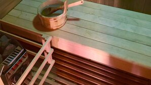 Una sauna con bancos de madera y un balde de madera con una cuchara.