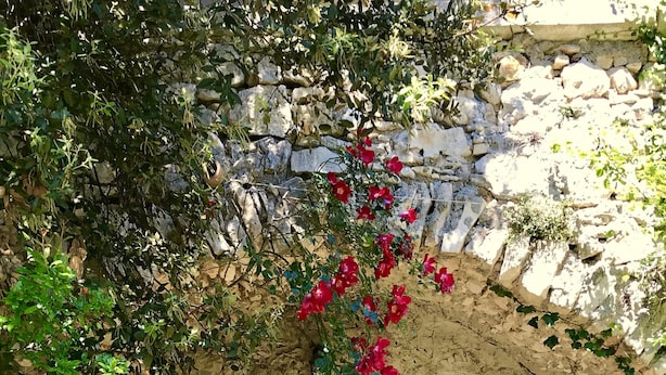 Pared de piedra con un sofá blanco y una silla de mimbre bajo un arco.