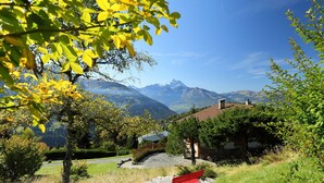 Un paysage paisible, avec une montagne en arrière-plan, un sentier pavé de pierres et un banc rouge.