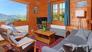 L’intérieur d’un chalet confortable, avec un canapé, un fauteuil et un téléviseur.