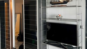 A room with a built-in shelving unit, a model ship, and a television. - Luxury studio 1st line Ocean for 2 persons (Biarritz)