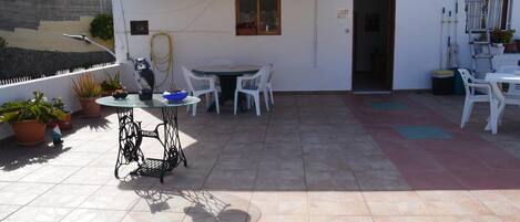 Un patio con una mesa, sillas, plantas en macetas y una escalera.