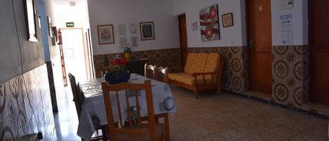 A dining area with a table set for two, a wooden chair, and a sofa.
