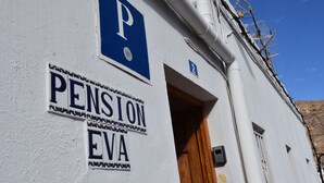 A building with a 'Pension Eva' sign and a 'P' sign indicating parking. - Pensión Eva (Mogan)