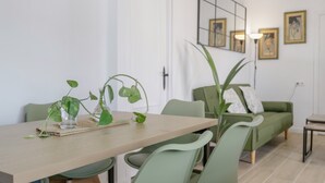 A dining area with a wooden table, green chairs, and potted plants.