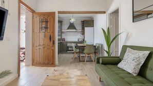 A modern interior with a wooden door, a dining area, and a green sofa.
