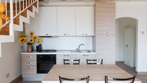 Una cucina moderna con mobili bianchi, un tavolo da pranzo e sedie.