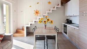 Una cucina moderna con mobili bianchi, un tavolo da pranzo in legno e una scala decorata con fiori.