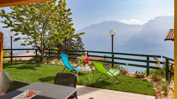 Patio esterno con tavolo e sedie, vista sulle montagne e un molo in legno.
