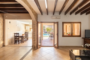 A spacious living area with a dining set, a glass door leading outside, and a television on a stand. - Stunning Holiday Home “Casa Magui” with Pool, Garden, Terraces & WiFi; Parking Available (Capdepera)
