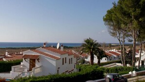 A coastal residential area with white houses, a pool, and a clear view of the sea.