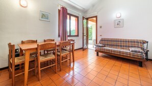 Zona pranzo con tavolo e sedie in legno, un divano e una porta che dà all'esterno.