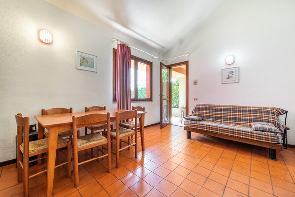 A dining area with a wooden table and chairs, a sofa, and a door leading outside.