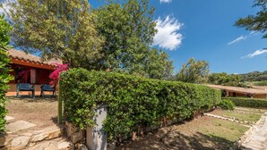 Una villa con un vialetto in pietra, una zona relax coperta e una vegetazione rigogliosa.