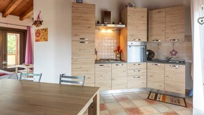 Een keuken met houten kastjes, een gasfornuis en een spoelbak.