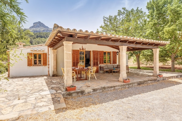 A stone patio with a pergola, outdoor furniture, and potted plants.