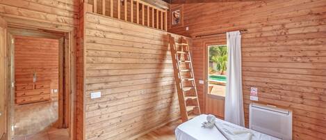 Une cabane en bois avec deux lits, une échelle et une fenêtre avec des rideaux.