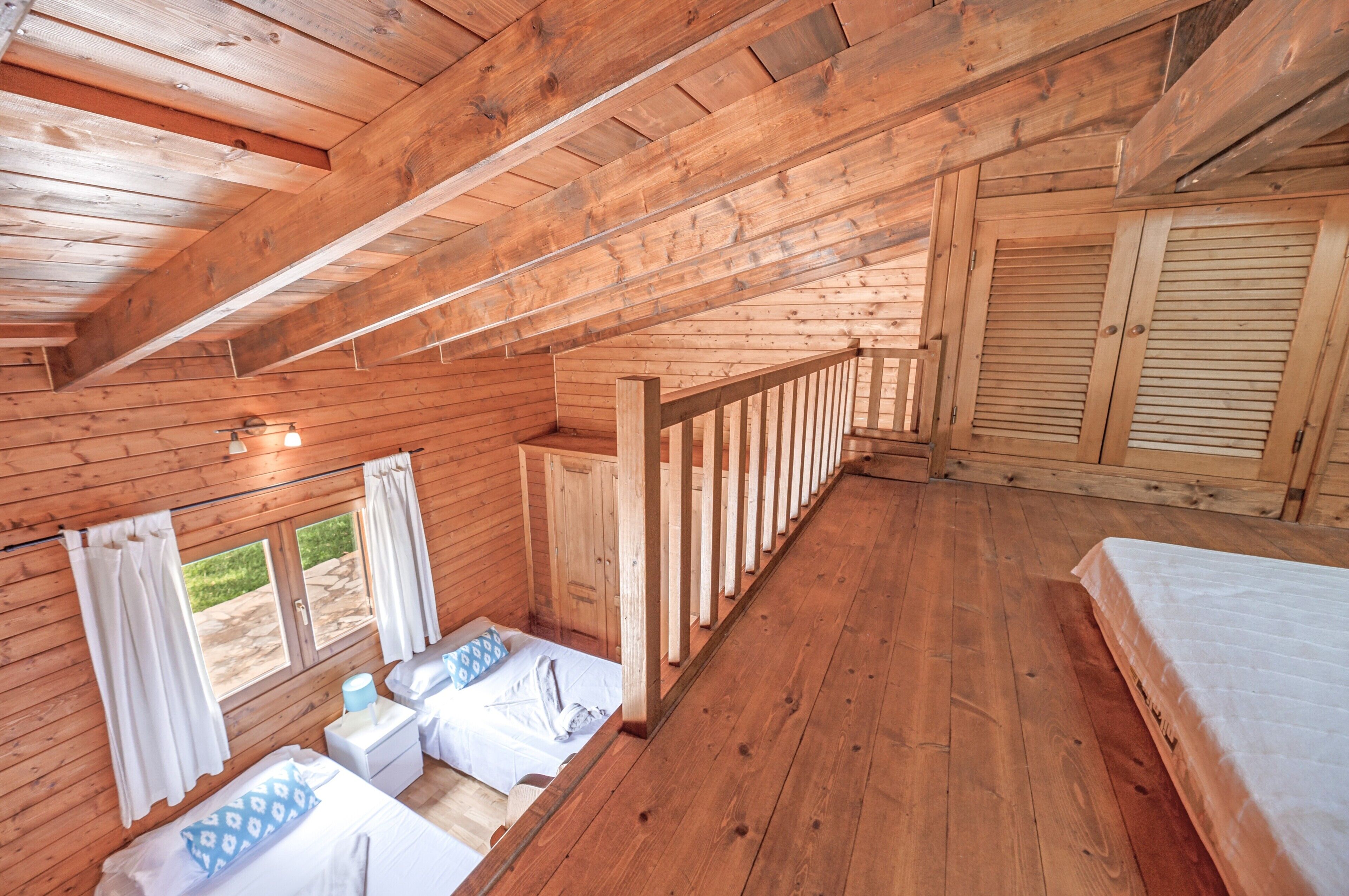 A wooden cabin with a loft bedroom, a small bathroom, and a balcony.