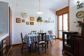 Zona pranzo con tavolo apparecchiato per quattro, sedie in legno, un lampadario e decorazioni a parete.