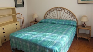 A bedroom with a bed, a wooden dresser, two bedside tables with lamps, and a framed picture on the wall. - Apartment "Golfo Stella" With Sea View and Near the Sea (CAPOLIVERI)