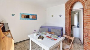 Une pièce avec une table blanche, un canapé à rayures bleues et blanches, un mur en briques et un petit miroir accroché au mur.