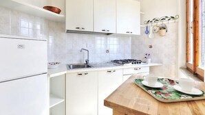 Une cuisine moderne avec des meubles blancs, un évier en acier inoxydable et un plan de travail en bois.