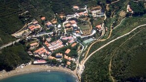 Une vue aérienne d’une ville côtière, avec une plage, des bâtiments aux toits rouges et des routes sinueuses.