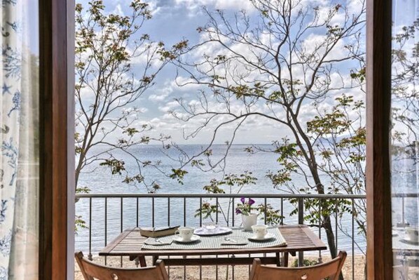 A balcony with a table set for dining, overlooking a body of water and trees.