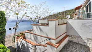 Un bâtiment situé sur la côte, avec une façade blanche, une antenne parabolique et une vue sur la mer.