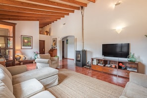 A living room with a fireplace, a television, and a wooden ceiling.