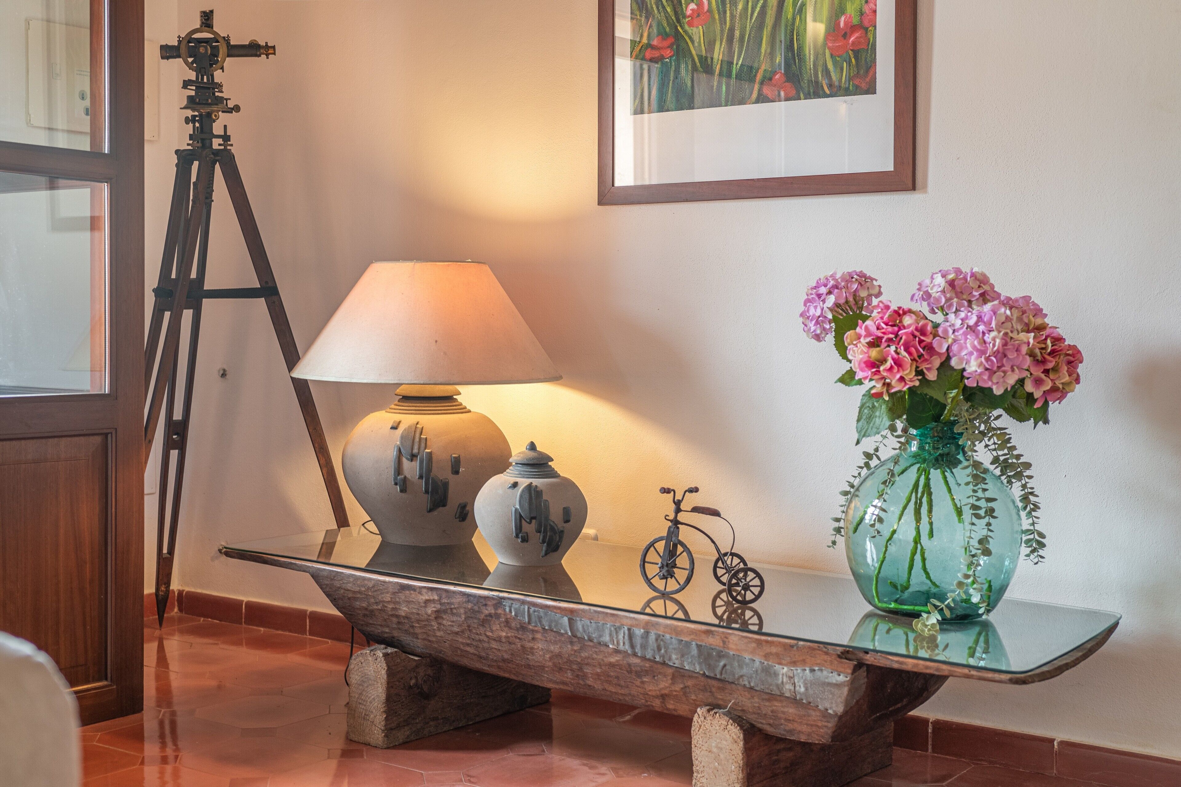 Une pièce comprenant un trépied, une lampe, un vase avec des fleurs et un vélo.