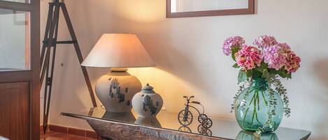 Une pièce comprenant un trépied, une lampe, un vase avec des fleurs et un vélo.