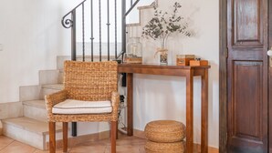 Ein Korbstuhl mit Kissen, ein Holztisch mit Vase und Dekoration, und eine Holztür.