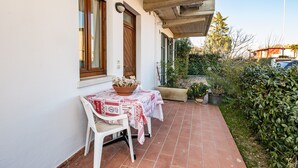 Une terrasse avec une table et des chaises, une porte en bois et une fenêtre avec des rideaux.