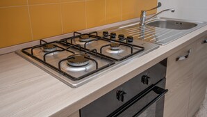 Une cuisine équipée d’une cuisinière à gaz, d’un évier et de meubles de rangement en bois.