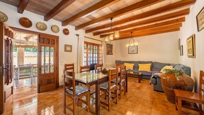 A dining area with a wooden table and chairs, a sofa, and a large vase. - Villa "La Plana" with Stunning Mountain Panorama and Pool (Pollensa)