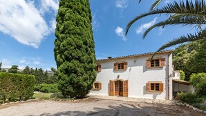 A two-story building with a white facade, wooden shutters, and a gravel driveway. - Villa "La Plana" with Stunning Mountain Panorama and Pool (Pollensa)