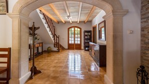 A hallway with a tiled floor, a wooden staircase, and a large arched doorway. - Villa "La Plana" with Stunning Mountain Panorama and Pool (Pollensa)