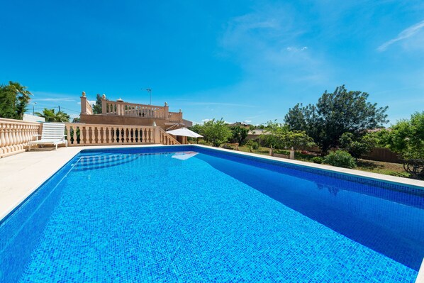 A swimming pool with a clear blue sky and a building in the background.
