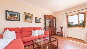 A living room with a red sofa, a glass coffee table, and a wooden cabinet.