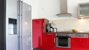A modern kitchen with red cabinets, stainless steel appliances, and a coffee maker. - Beach house, 200 sqm. Wf., Directly at the Plauer See, Müritz, 30m to the beach (Fünfseen Lenz Süd)