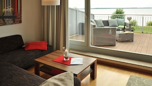 A modern living room with a sofa, a wooden coffee table, and a balcony with outdoor furniture. - Beach house, 200 sqm. Wf., Directly at the Plauer See, Müritz, 30m to the beach (Fünfseen Lenz Süd)