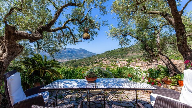 Una mesa con sillas, vistas a un pueblo y árboles.