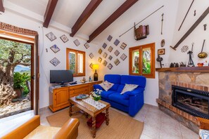A living room with a blue sofa, wooden coffee table, television, fireplace, and decorative wall tiles.